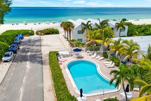 Un complejo turístico con piscina, playa y coches aparcados.
