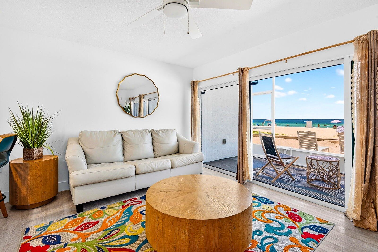 A modern living room with a sofa, coffee table, and a view of the beach.