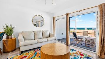 A modern living room with a sofa, coffee table, and a view of the beach.