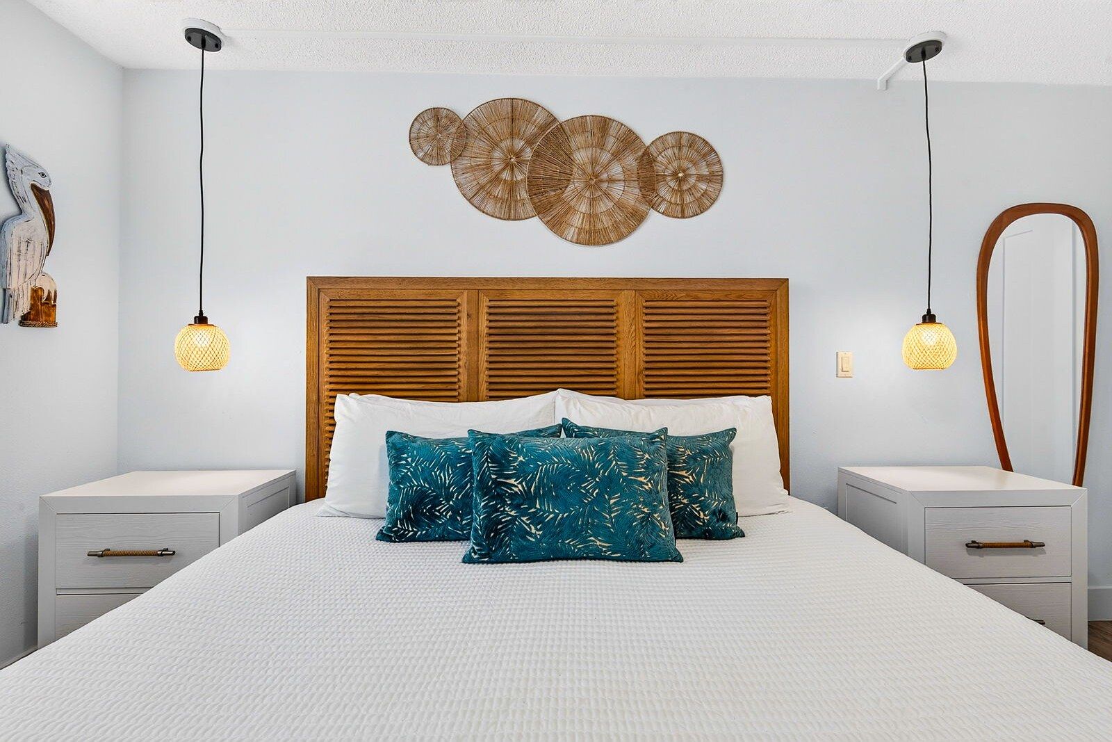 A neatly arranged bedroom with a wooden headboard, white bedding, and decorative wall art.