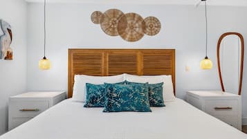 A neatly arranged bedroom with a wooden headboard, white bedding, and decorative wall art.