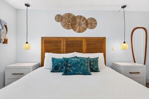 Een keurig opgemaakt slaapkamer met een houten hoofdbord, witte beddengoed en decoratieve wandkunst.