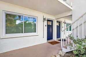 A building entrance with a concrete porch, a blue door, and a white railing.