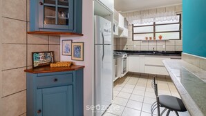 Una cocina con refrigerador, estufa y una ventana con cortinas.