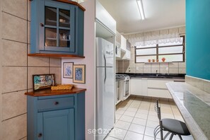 Une cuisine équipée d’un réfrigérateur, d’une cuisinière et d’une fenêtre avec des rideaux.