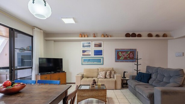 Una sala de estar con televisor, sofá y comedor.