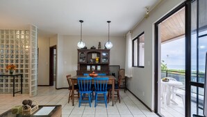 Un comedor con una mesa de madera y sillas azules, una mesa baja de vidrio y un armario con puertas de cristal.