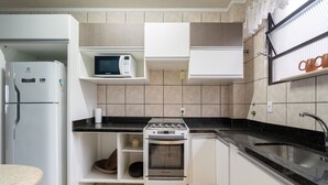 Cocina compacta con refrigerador, microondas, estufa, horno y pileta.