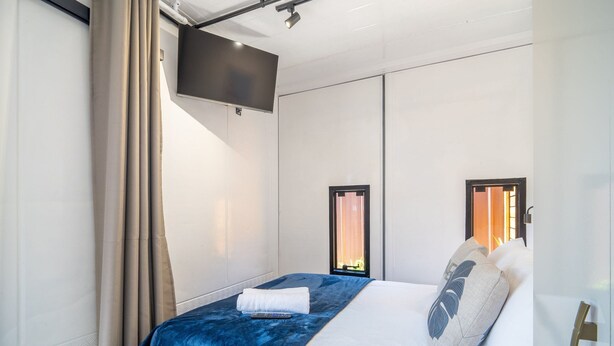 Una habitación de hotel moderna con una cama grande, un televisor de pantalla plana en la pared y una ventana con cortinas.