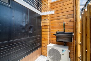 A sauna with a black exterior, wooden walls, a white air conditioning unit, and a black sink. - Chalet 200m fr/ Campeche Beach w/ Garage Scj0008 (Florianópolis)