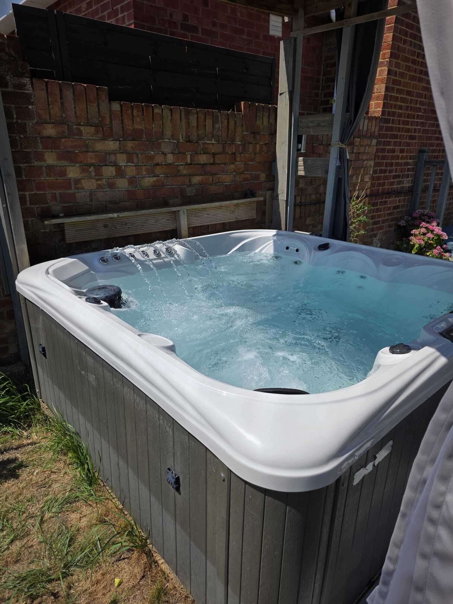Ein Whirlpool in einer Außenanlage mit einer Ziegelwand und einem Holzdeck.