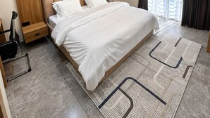 A modern bedroom with a large bed, wooden panel walls, an air conditioning unit, and a patterned rug. - Futuretrendhomes (Abuja)