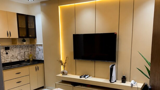 A modern kitchen with a flat-screen TV, built-in cabinets, and a marble backsplash. - Futuretrendhomes (Abuja)