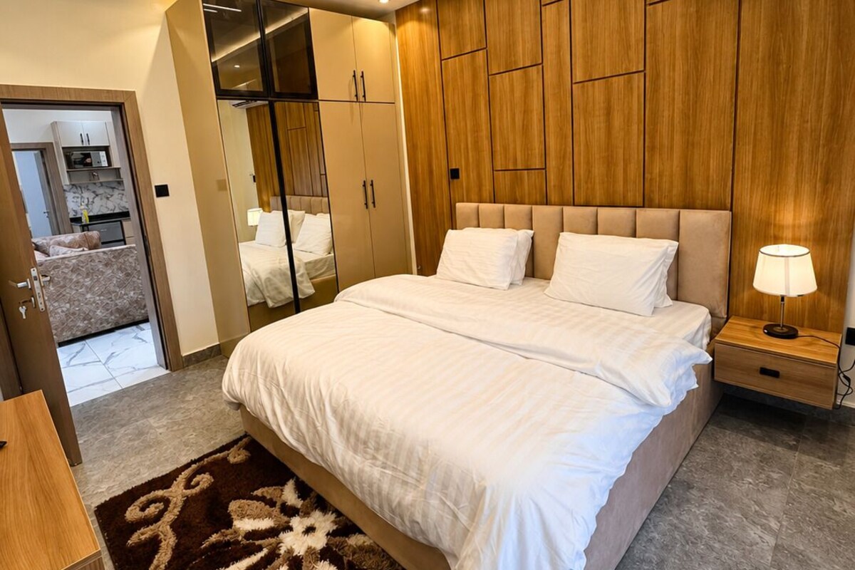 Ein modernes Schlafzimmer mit einem großen Bett, einer Holzwand, einem Einbauschrank und einer Klimaanlage.