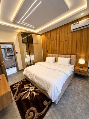 Ein modernes Schlafzimmer mit einem großen Bett, einer Holzwand, einem Einbauschrank und einer Klimaanlage.