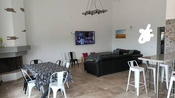 Un salon moderne comprenant un canapé, une table à manger, des chaises, un téléviseur et une cheminée.