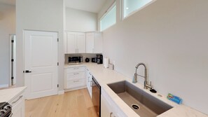 A modern kitchen with white cabinetry, a stainless steel sink, and a built-in microwave. - Twice is Nice by Avantstay Gourmet Kitchen + Heated Baths Downtown Paso Robles Wine Country (Paso Robles)