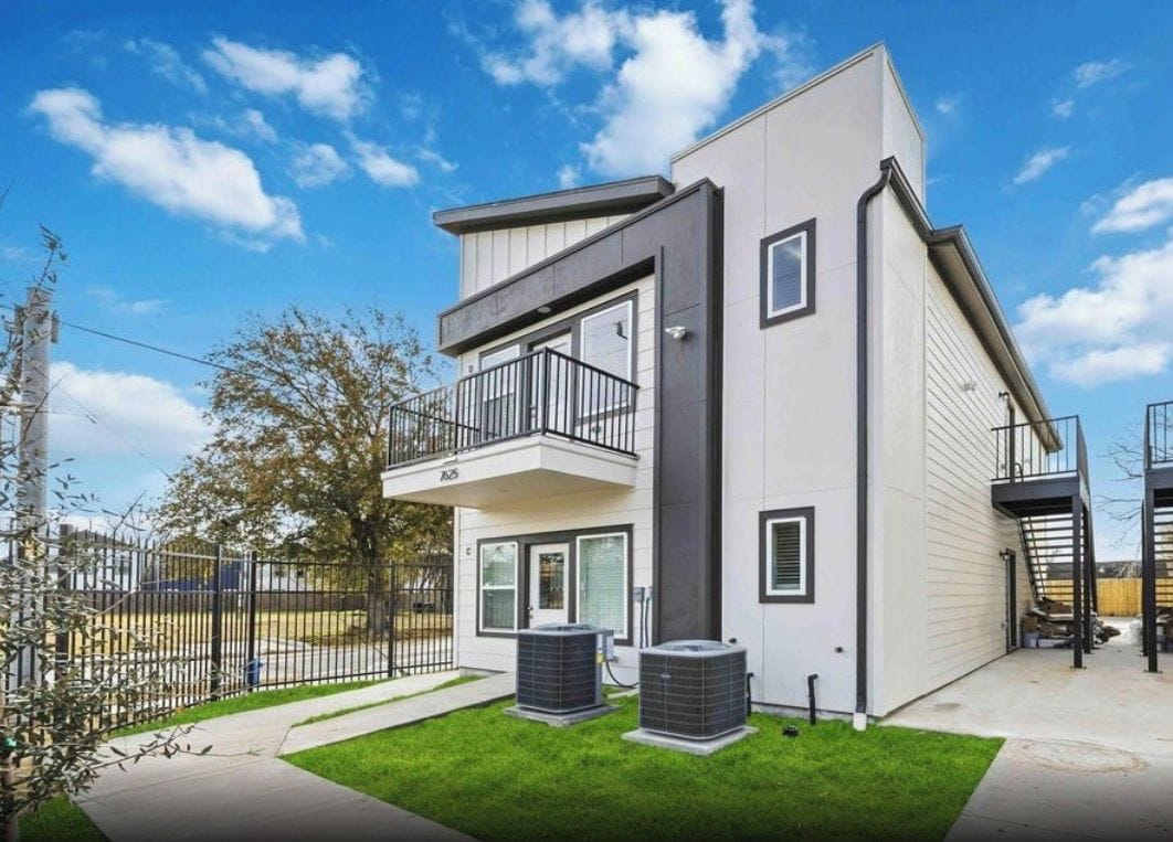 Ein modernes Wohnhaus mit zwei Etagen, einem Balkon, einem eingezäunten Garten und zwei Klimaanlagen.