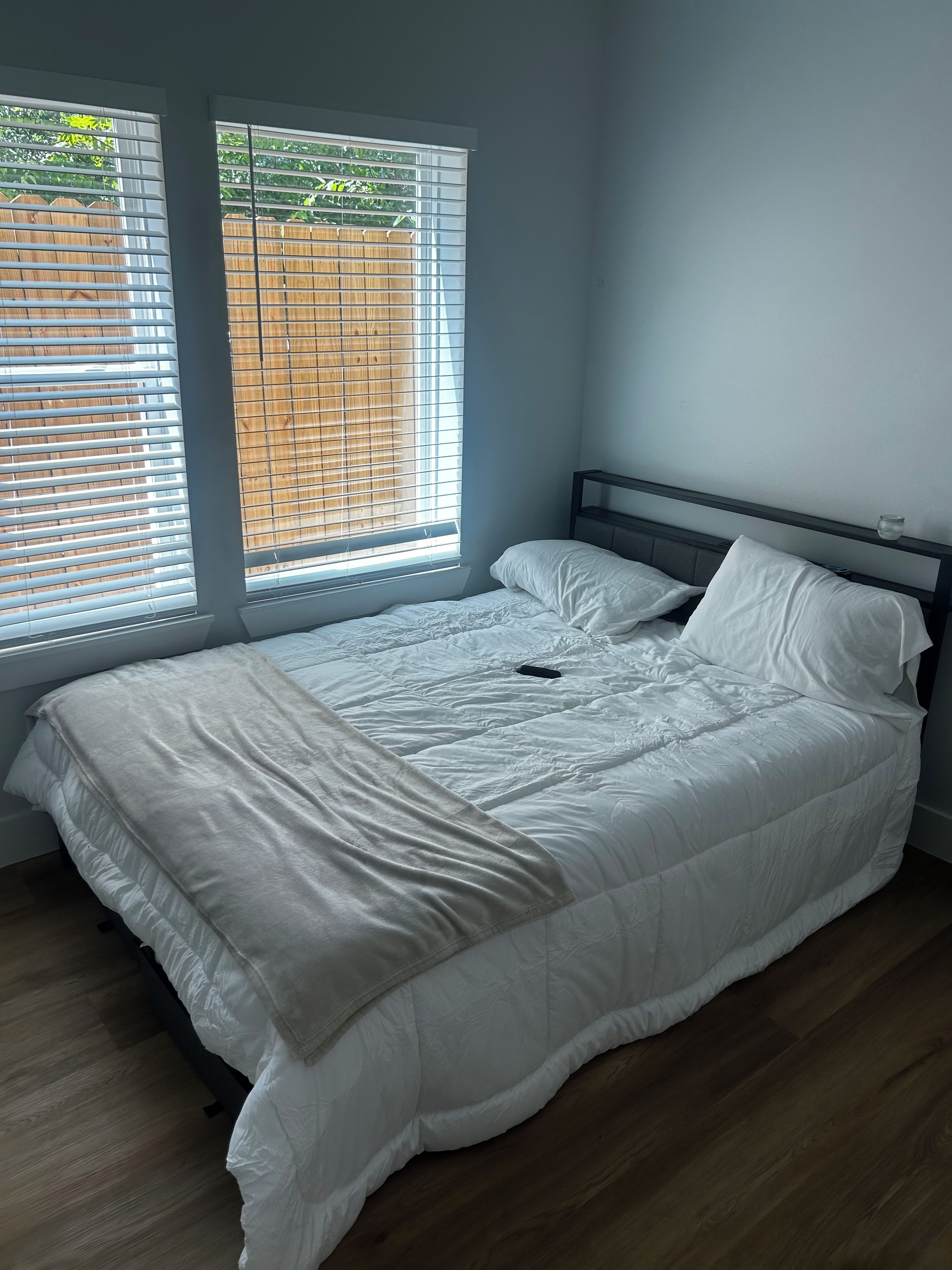 Ein Schlafzimmer mit einem Bett, einem Nachttisch und einem Fenster mit Jalousien.