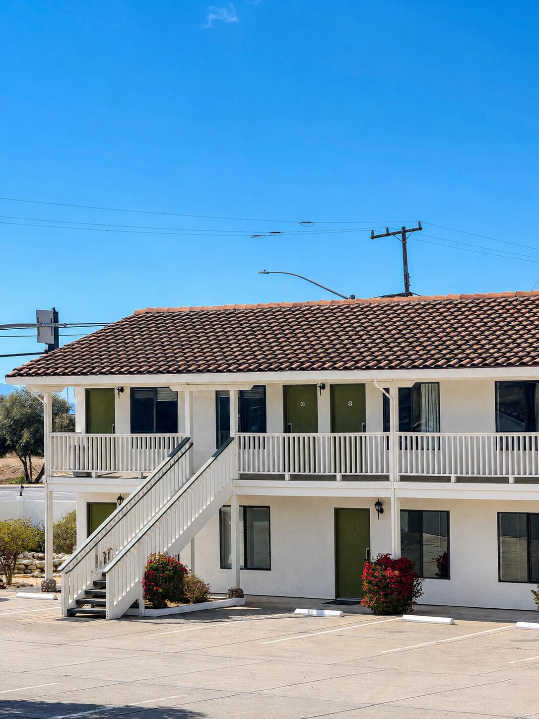 A two-story building with a tiled roof, a front staircase, and a parking lot.