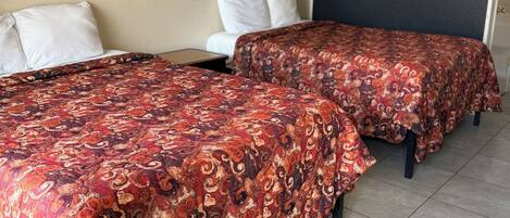 A hotel room with two beds, a dark wall, and a single artwork.