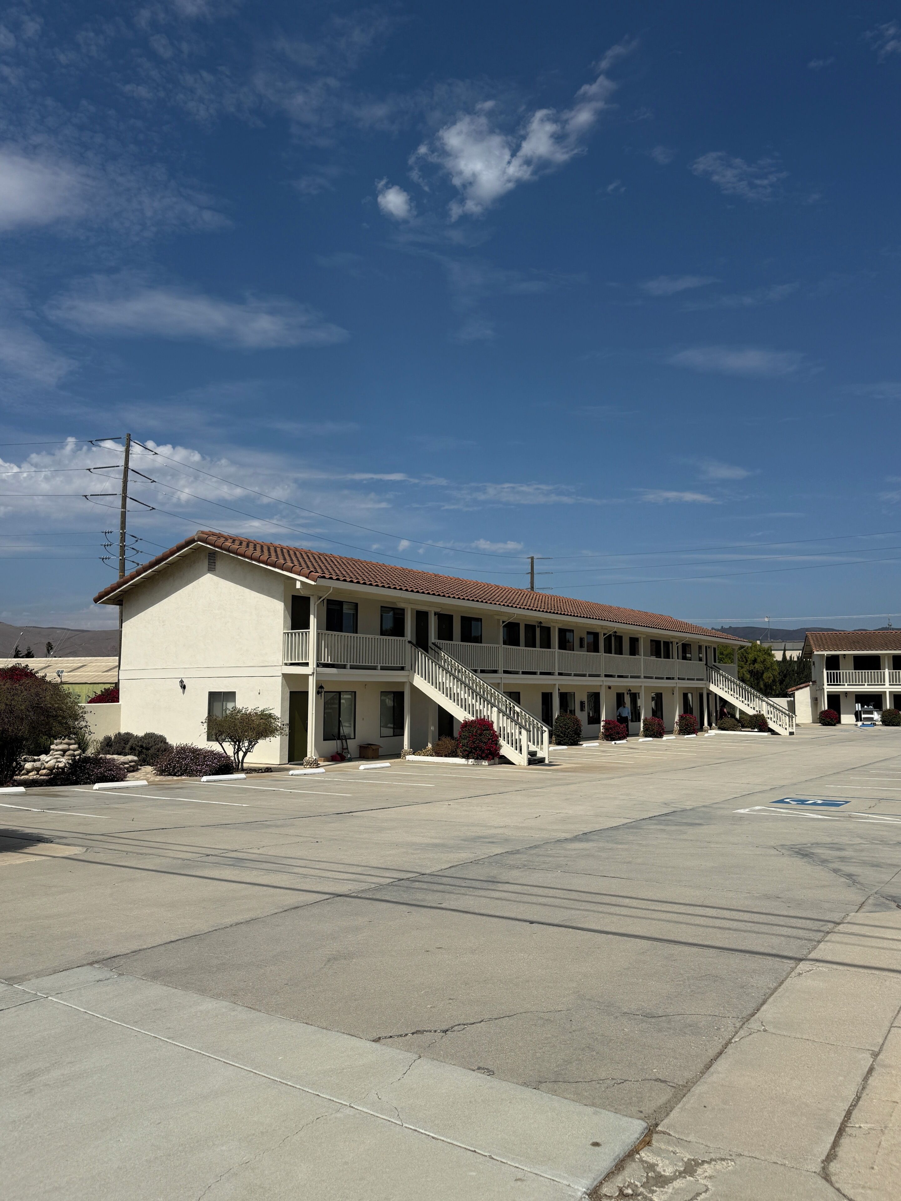 A two-story motel with a parking lot and a clear sky.