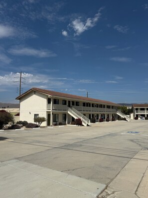 A two-story motel with a parking lot and a clear sky. - Motel 8 Soledad (Soledad)