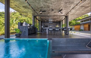 Une cuisine extérieure moderne avec une piscine, un coin repas et un ventilateur de plafond.