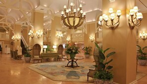 A spacious lobby with a grand chandelier, multiple seating areas, and decorative wall sconces. - Orlando | Compact Disney Retreat | Pool + Waterpark (Lake Buena Vista)