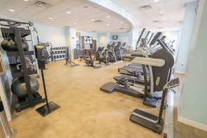 Ein Fitnessstudio mit Laufbändern, Crosstrainern und Krafttrainingsgeräten.