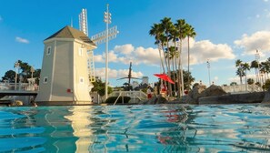 A swimming pool with clear water, a lifeguard tower, palm trees, and a small building with a sloped roof. - Orlando | Romantic Park Retreat | Pool + Waterpark (Lake Buena Vista)
