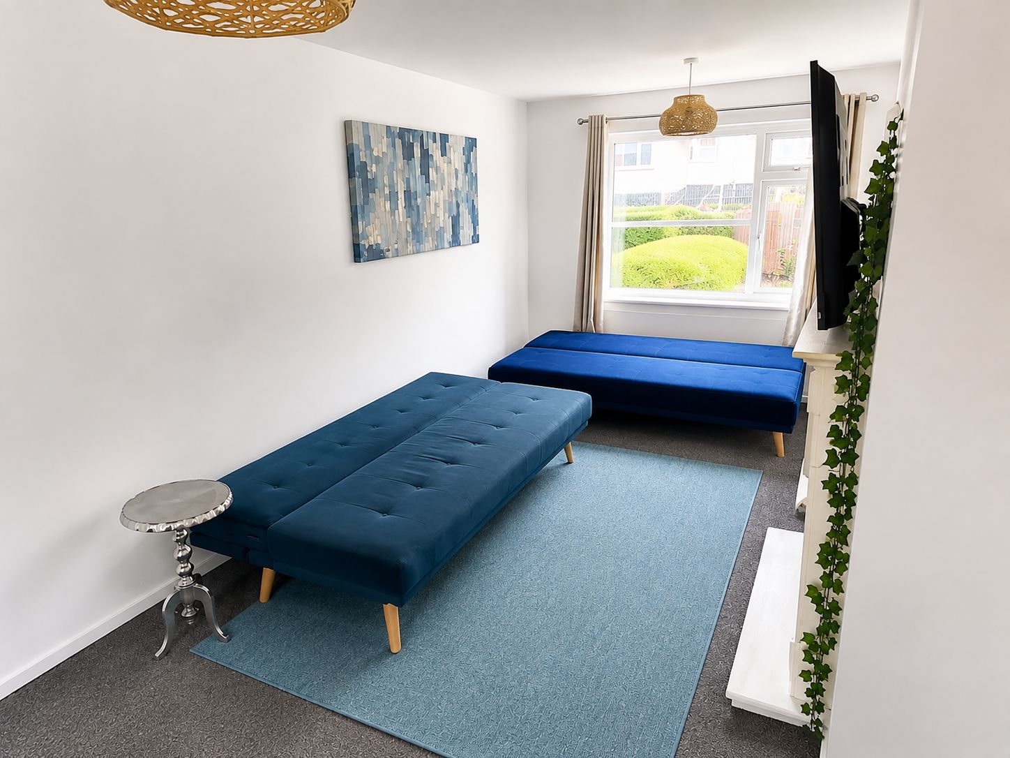 A room with a bed, a small table, a television, and a window with curtains.