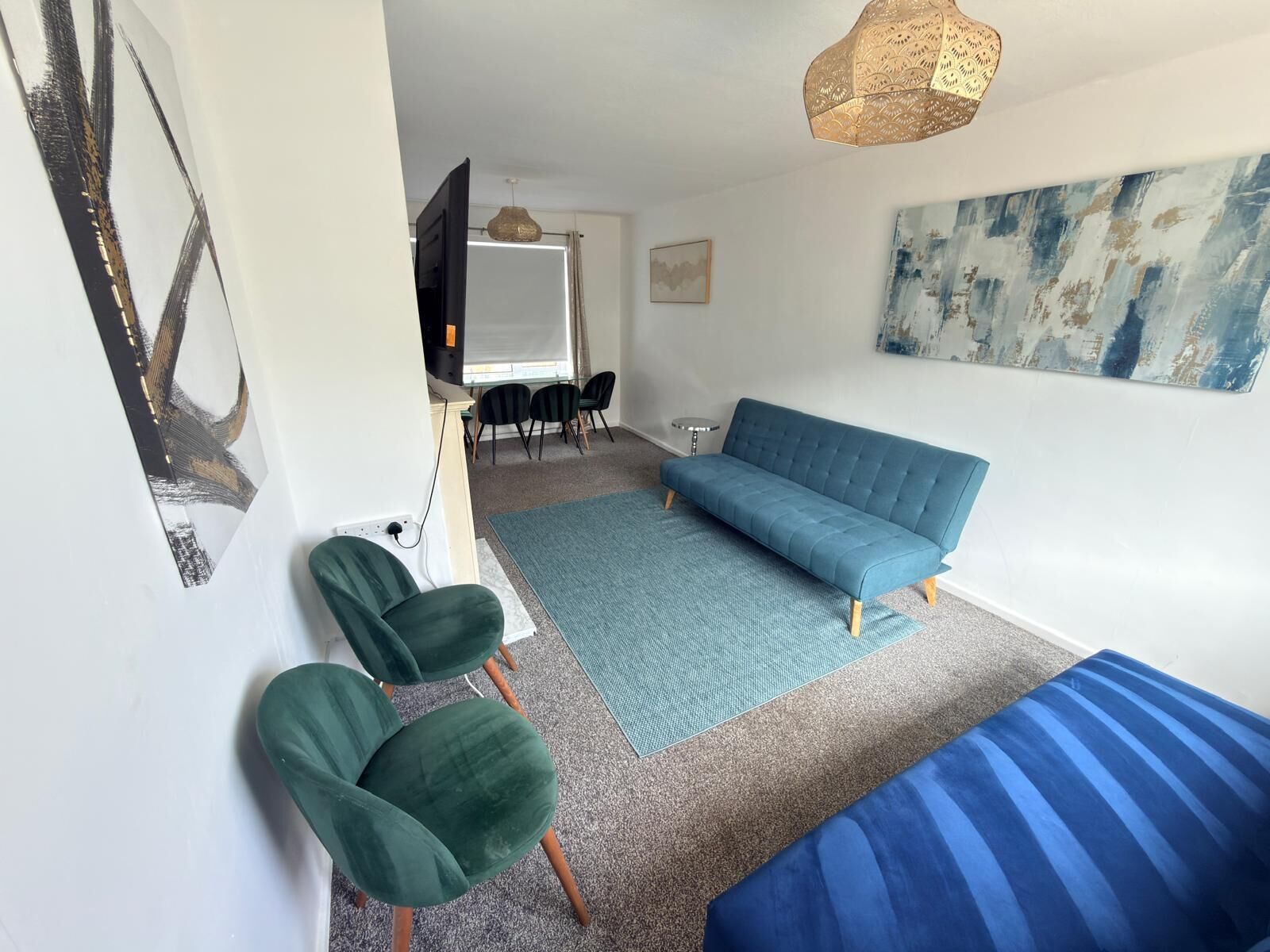 A modern living room with a sofa, chairs, a rug, and artwork on the walls.