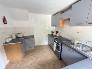 Une cuisine de taille réduite, équipée d’une cuisinière, d’un évier et de placards.