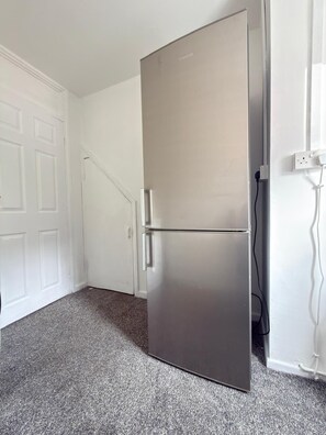 Ein Edelstahl-Kühlschrank in einem Raum mit weißen Wänden und Teppichboden.