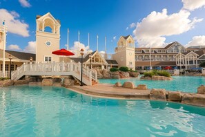 Ein Resort mit großem Pool, einem Glockenturm und einer Brücke.