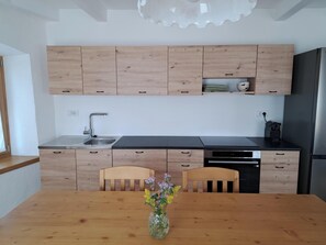 Una cocina moderna con armarios de madera, un lavamanos de acero inoxidable y un lavavajillas integrado.