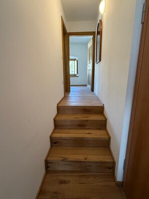 Una escalera de madera que lleva a una habitación con una puerta y un ventanal.