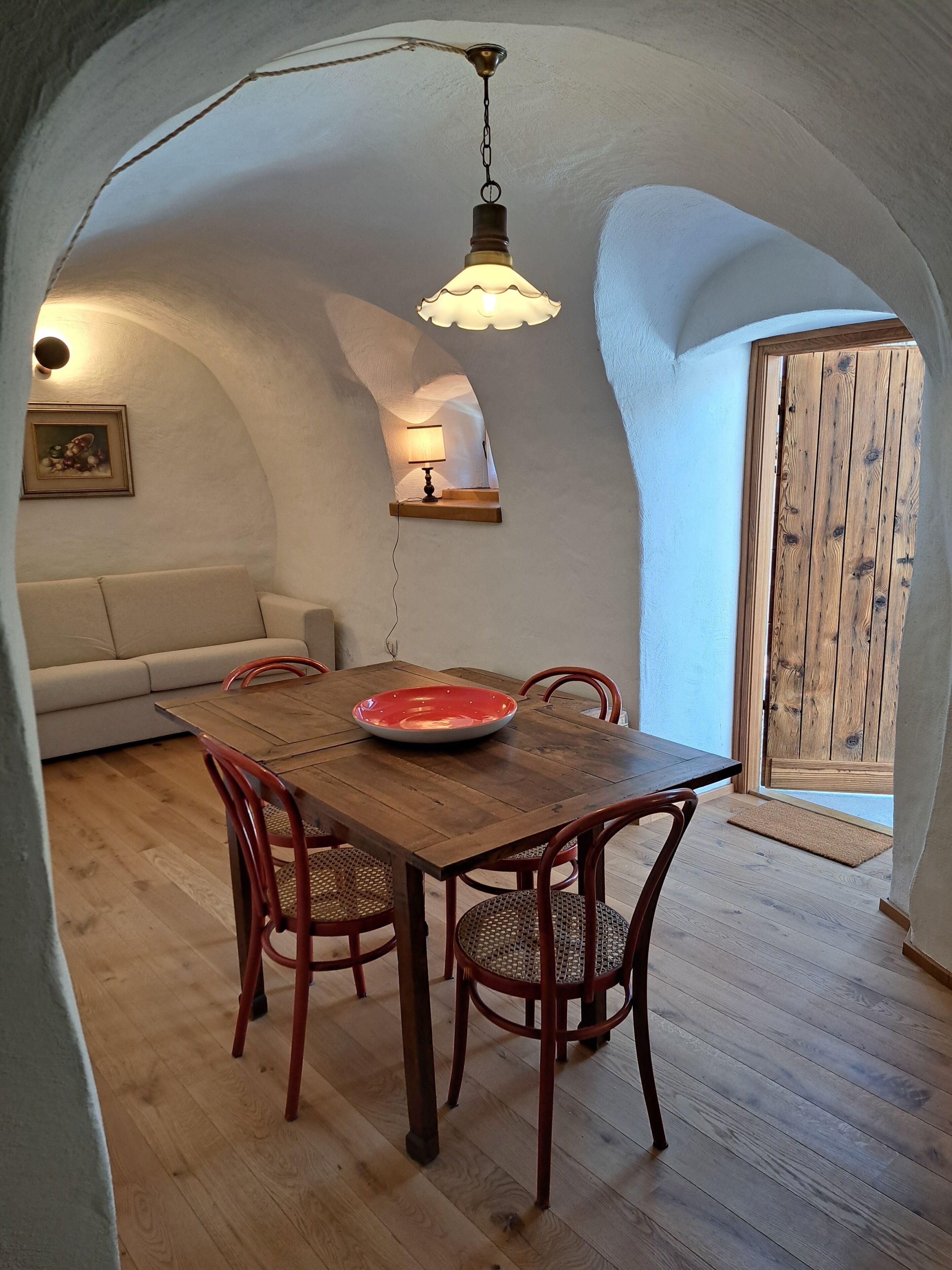 En mysig matplats med ett träbord, röda stolar och en hängande lampa.