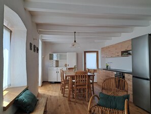 Eine moderne Küche mit einem eingebauten LG-Kühlschrank, Holzschränken und einem Essbereich mit Holztisch und Stühlen.