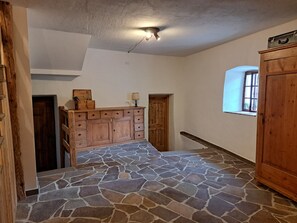 Ein Korridor mit Steinboden, Holzschränken und einer Deckenleuchte.