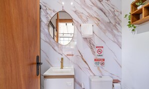 A bathroom with a marble wall, a sink, a toilet, and a mirror. - Chalet w/ Parking 200m From the Beach Scj0003 (Florianópolis)