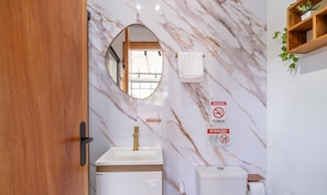A bathroom with a marble wall, a sink, a toilet, and a mirror. - Chalet w/ Parking 200m From the Beach Scj0003 (Florianópolis)