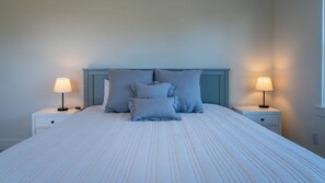 A neatly made bed with a headboard, two bedside tables with lamps, and a window on the right. - Graceful Oaks by Avantstay Pool + Oak Trails + Lawn Games Near Paso Robles (Paso Robles)