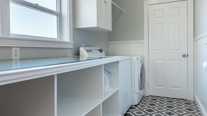 A laundry room with a washing machine, a dryer, and a glass-top counter. - Graceful Oaks by Avantstay Pool + Oak Trails + Lawn Games Near Paso Robles (Paso Robles)