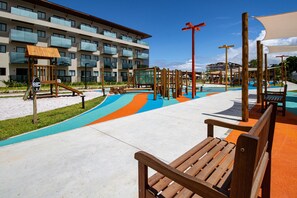 A playground area with a slide, climbing structures, and a bench.
