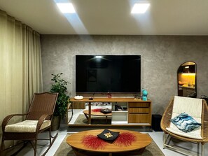 A living room with a flat-screen TV, a wooden coffee table, wicker chairs, and a potted plant. - Beachfront Condos at Ipioca Beach Life Maceio by MME (Maceió)