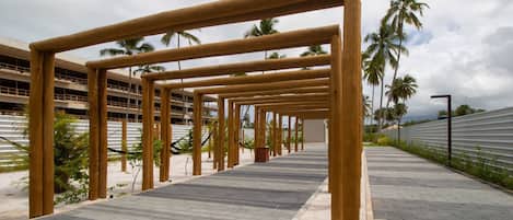 A pathway with wooden structures, palm trees, and a building in the background.