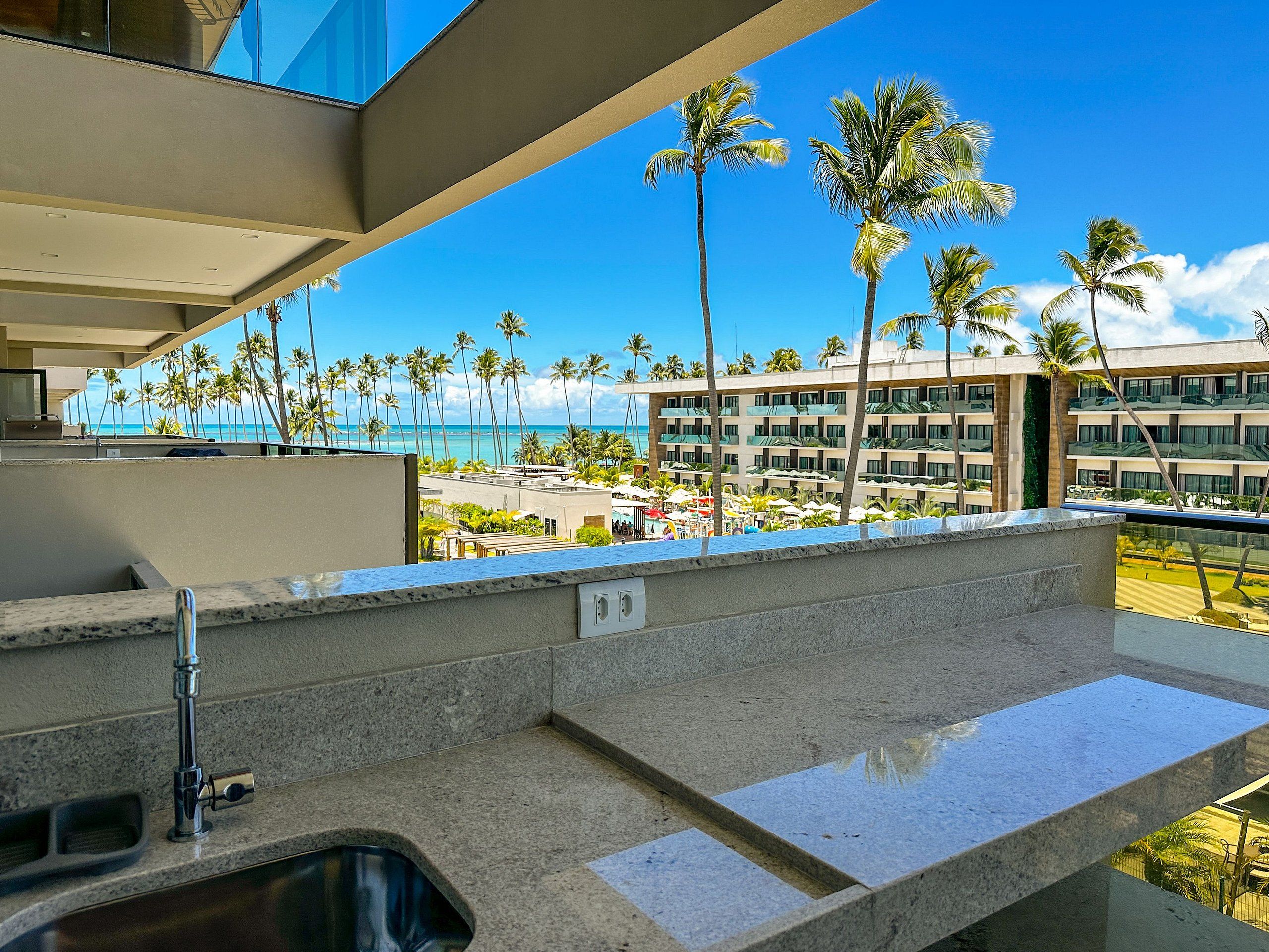 Un balcone moderno d'hotel con vista sull'oceano e sulle palme.