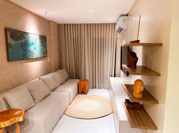 Una sala de estar moderna con un sofá, una mesa de centro, un televisor montado en la pared y un estante decorativo.